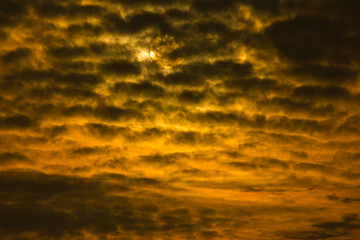 dramatic sunset or sunrise with golden sky and black clouds forming a abstract with sun in the background. 