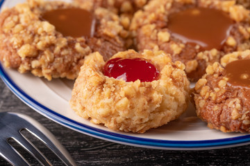 Shortbread cookies made of walnut dough with strawberry jam on a plate with a fork. Blueberries on a red napkin.