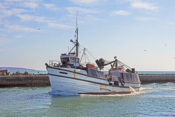 Old, white fishing trawler entering harbour
