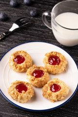 Shortbread cookies made of walnut dough with strawberry jam on a plate with blueberries and a fork.