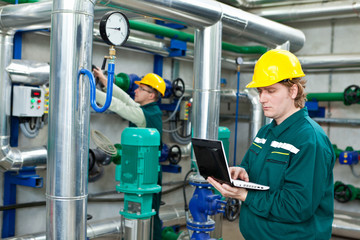 Two men working in a factory, controls the operation of devices in a Heating Plant or Refinery....