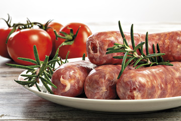 salsicce crude con rosmarino e pomodori nel piatto fronte da vicino
