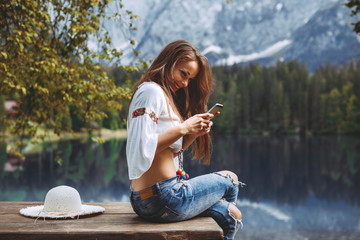 Young woman on the lake using smartphone