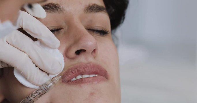 Lip Augmentation. The doctor cosmetologist makes lip augmentation procedure of a beautiful woman in a beauty salon. Cosmetic beauty injection concept