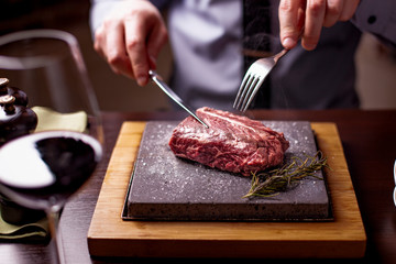 sirloin steak on a very hot stone being cooked by a man to his own taste on a wooden table with a...