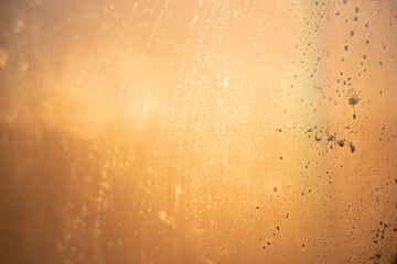 Abstract texture, orange, metallic, spots on the misted glass.