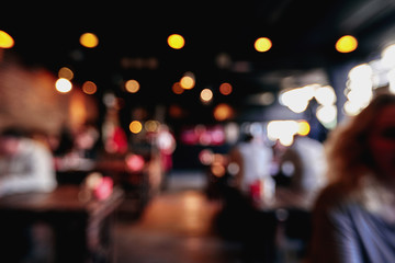 Blurred restaurant or cafe background. Tables and chairs in the lobby of the mall. Visitors to the restaurant for dinner. Beautiful bright interior.