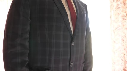 man button up his buttons on his jacket, close-up. businessman puts on a blue jacket in cage. office worker gets dressed in the morning. concept of stylish and fashionable clothes for men