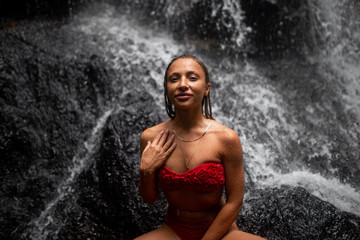 Fototapeta na wymiar fashion portrait of beautiful woman with brunette hair in red swimwear posing on background of waterfall in Bali