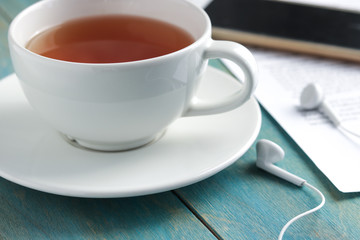 cup of tea smartphone headphones on wooden table soft focus close ups