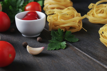 pasta ingredients fettuccine cherry tomatoes garlic parssley on wooden table