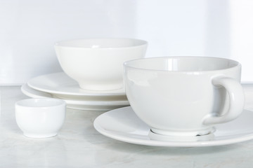 set of white dishes. empty cup bowls plates on the table soft focus