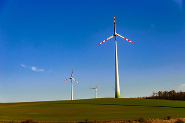 Windmill in a green field against a blue sky. Naturally friendly resource extraction systems.