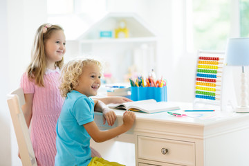 Child drawing rainbow. Kid painting at home. Little girl and boy doing homework after school. Kids desk with abacus in white sunny bedroom. Children study, learn to read and write. Bedroom for student