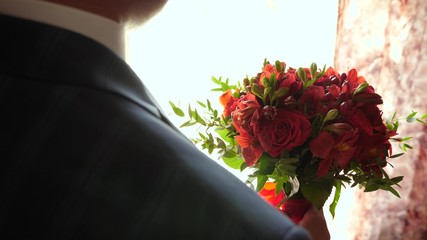 beautiful bouquet of red roses in hands of man in jacket and white shirt. close-up. beautiful flowers in hands of man gift for his beloved woman. groom with flowers
