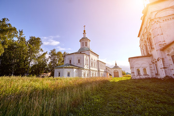 Old orthodox church at village. Summer view with floral meadow. Sun flare