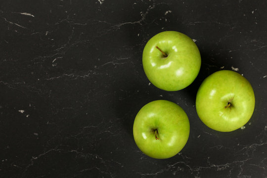 Overhead Shot - Three Green Apples On Black Board, Space For Text On Left Side.