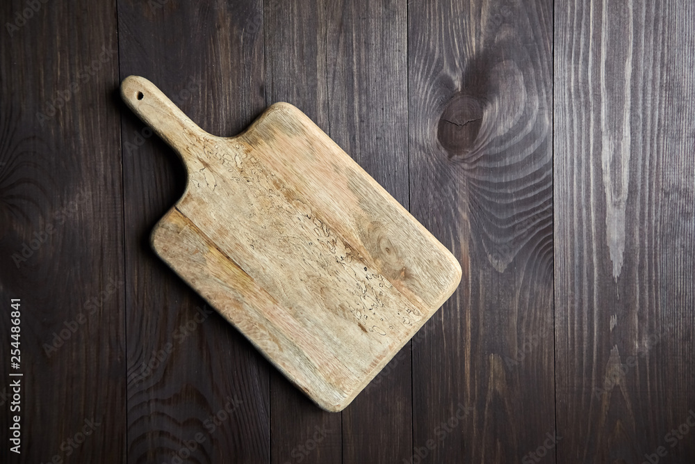 Wall mural Cutting board from pine wood is on brown table. Top view