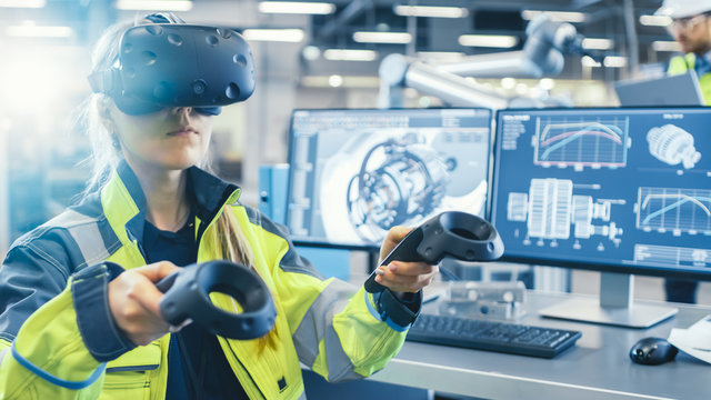 Factory: Female Industrial Engineer Wearing Virtual Reality Headset and Holding Controllers, She Uses VR technology for Industrial Design, Development and Prototyping in CAD Software.