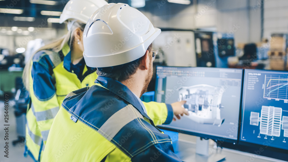 Poster at the factory: male mechanical engineer and female chief engineer work together on the personal com