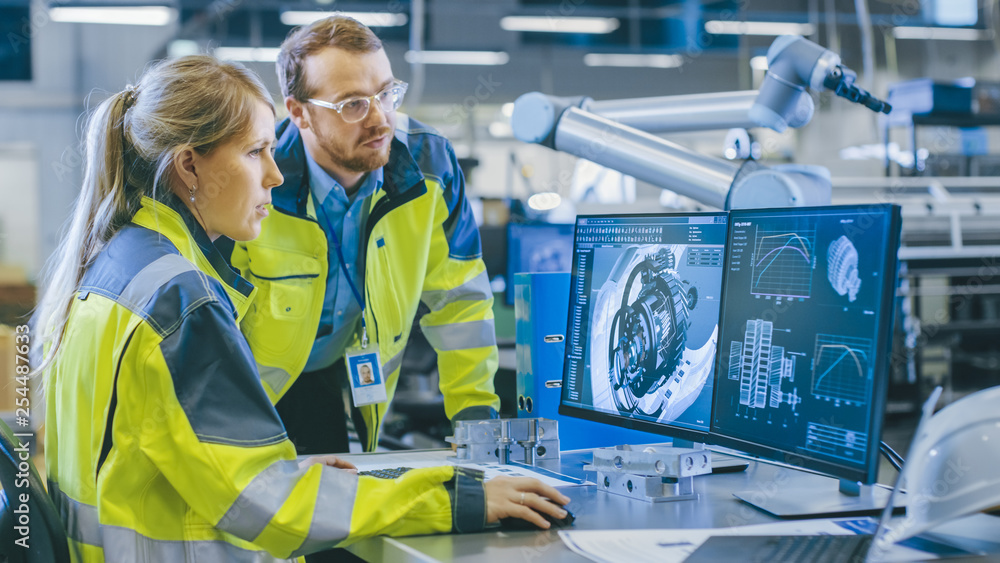 Poster at the factory: male mechanical engineer and female chief engineer work together on the personal com