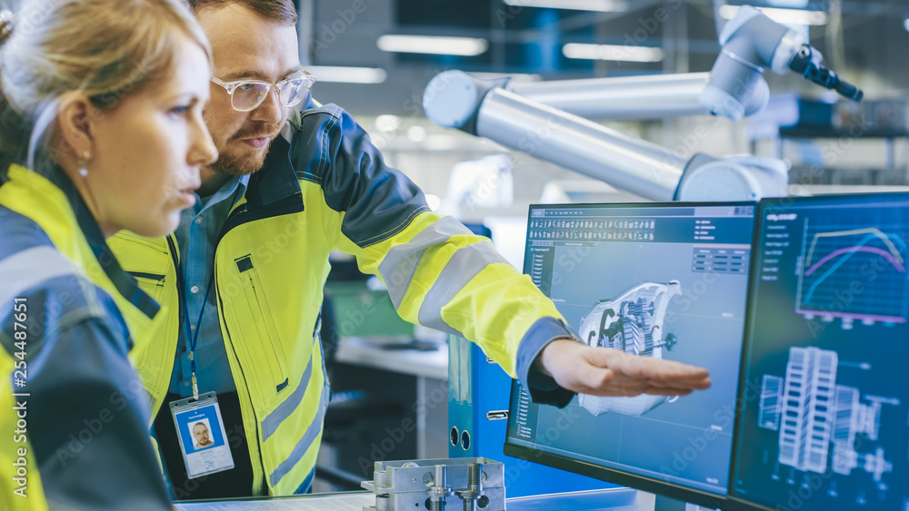 Aufkleber at the factory: male mechanical engineer and female chief engineer work together on the personal com