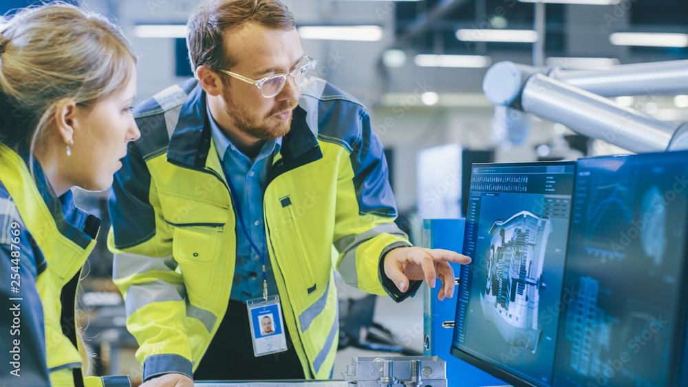 Aufkleber at the factory: male mechanical engineer and female chief engineer work together on the personal com