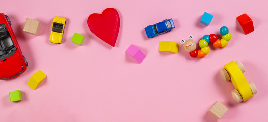 Baby kid toys banner background. Wooden toys, cars, colorful blocks on pink background