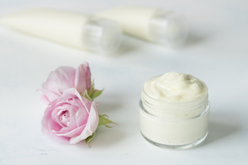 Fototapeta na wymiar Natural face and body cream in a jar with a rose flower next to on a white background