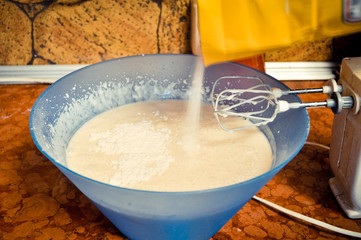 dough for pancakes, whipped with a mixer in a blue salad bowl. concept of home food.