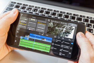 Black smartphone in hand. On-screen video editing program