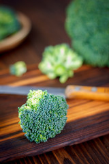 Fresh broccoli cutted on the kitchen board by knife.