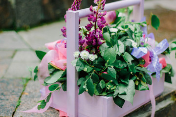 Fototapeta na wymiar Beautiful flowers in a purple wooden basket outdoors.