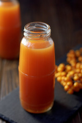 Sea buckthorn juice in a jar on a dark wooden background.