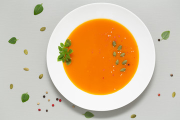 Pumpkin soup with herbs, cream and pumpkin seeds served in white bowl. Seasonal autumn food - Spicy...