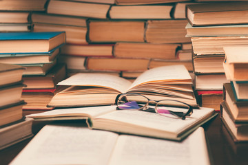 Open book and glasses on wood desk in the library room with blurred focus for education background and back to school concept