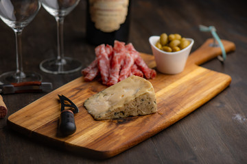 Cheese plate with wine in the background on a dark wood table.​