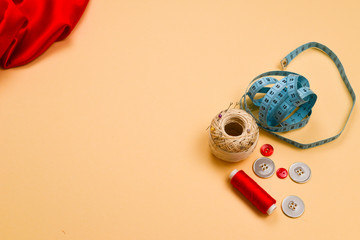 Threads, buttons, red fabric, measuring tape. Copy space.