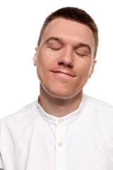 Obraz premium Charming handsome young man in a white shirt is making faces, while standing isolated on a white background