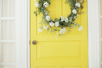 Beautifully decorated farmhouse look. Bright yellow door, a spring greenery wreath of flowers, a...