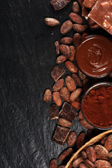 Melting chocolate or melted chocolate with a chocolate swirl and stack, chips and powder on black