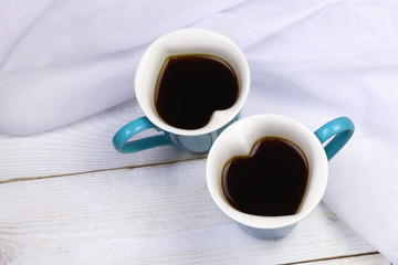 Two heart shaped coffee cups on white wooden background. Love and romantic concept mockup.