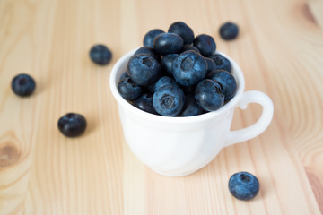 Blueberries in a white mug on a wooden background with copy space