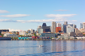 Fototapeta premium A motorboat in Puget Sound bay waters and Seattle downtown on background. Seattle pier and skyscrapers under afternoon sun.