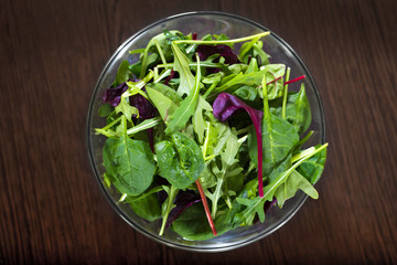 Mixed leaves of a diet salad on a wooden table. A view from above.
