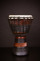 African drum djembe made of brown wood on a dark background