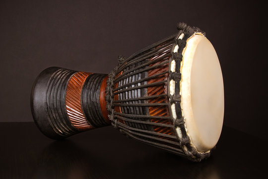 African drum djembe made of dark wood on black background