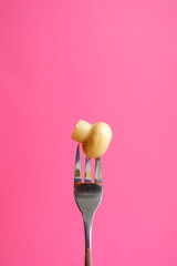 Marinated mushroom on a fork. Food on a pink background