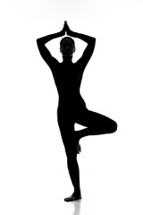 Yoga fan. Shot of a silhouette of a slim sporty female practicing tree yoga pose