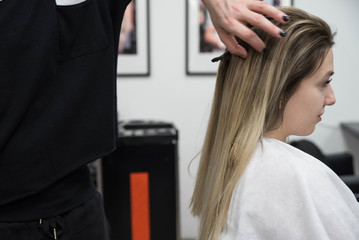 Fototapeta premium Professional hairdresser drying woman's hair with hairdryer in beauty salon after beauty procedures and hair coloring